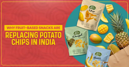 Image promoting fruit-based snacks in India, featuring colorful packages of mango, pineapple, and banana chips surrounded by fresh fruits. Bold text on red background reads: 'Why fruit-based snacks are replacing potato chips in India