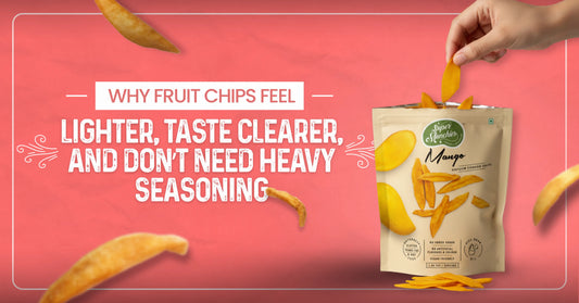 A hand places a mango chip into an open beige snack bag, surrounded by floating chips. Text: "Why fruit chips feel lighter, taste clearer, and don’t need heavy seasoning