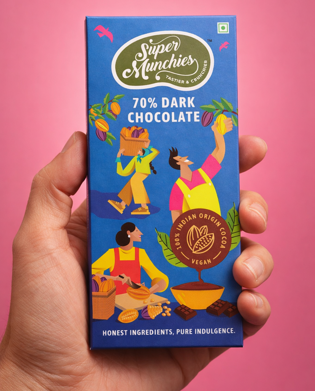 Hand holding a Super Munchies 70% Dark Chocolate bar packaging against a pink background