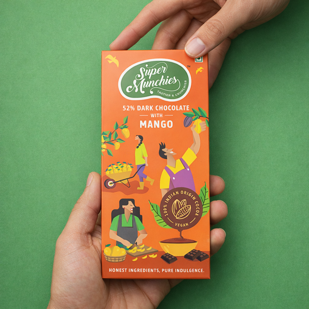 Hand holding a Super Munchies 52% dark chocolate with mango packaging against a green background