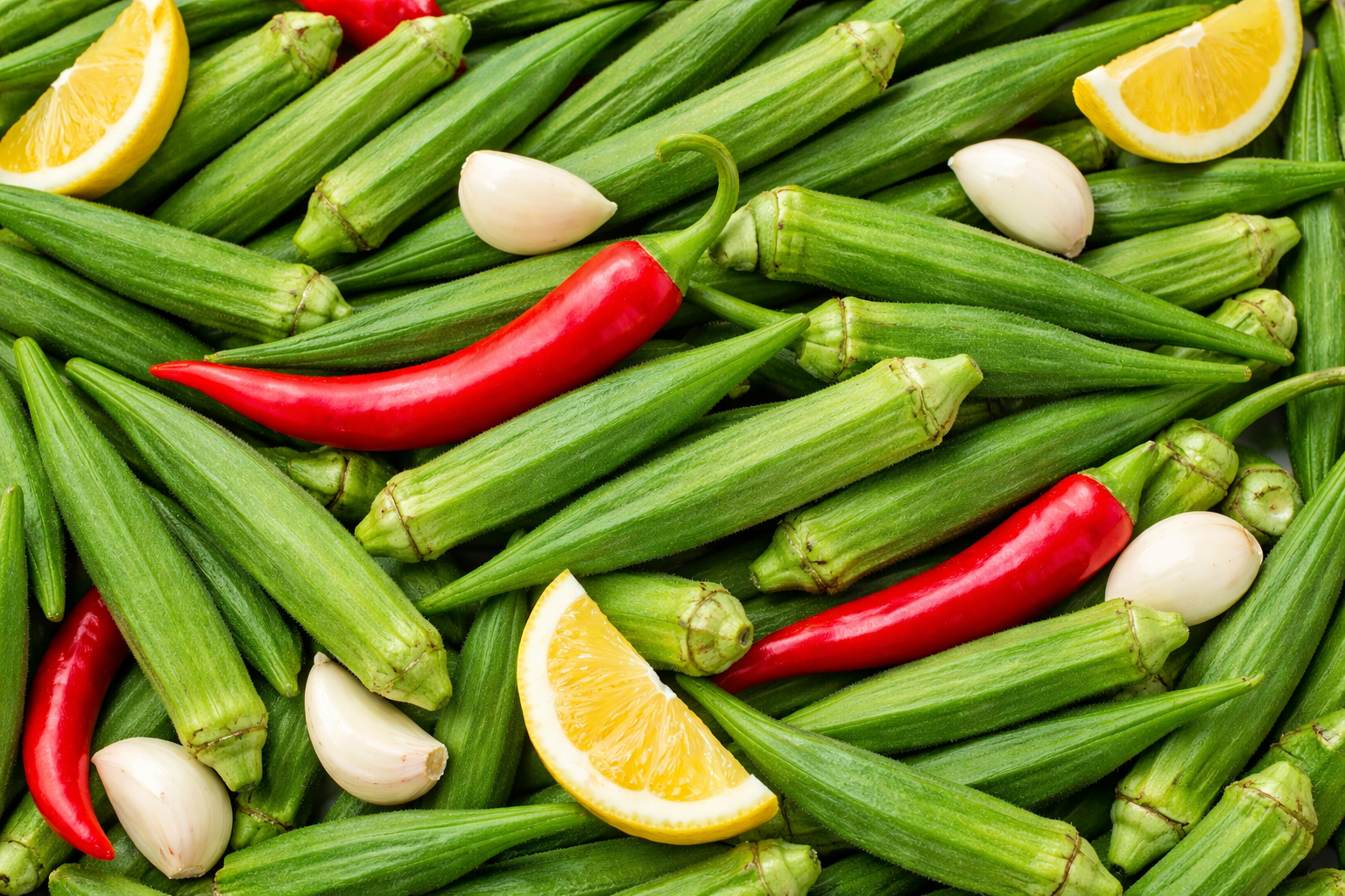 Assorted vegetables including okra, red peppers, garlic, and lemon slices  
